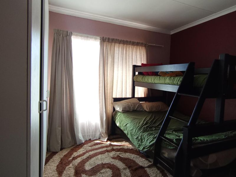 A bedroom featuring a built-in wardrobe and cove cornice detailing, with natural light entering through a window.