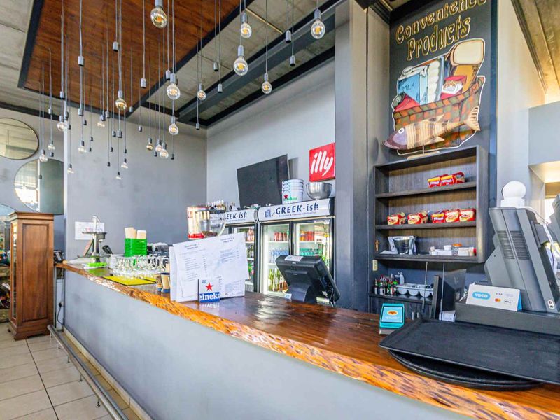 A commercial bar area featuring a timber-topped counter, built-in shelving, and modern pendant lighting, suitable for hospitality or entertainment use.