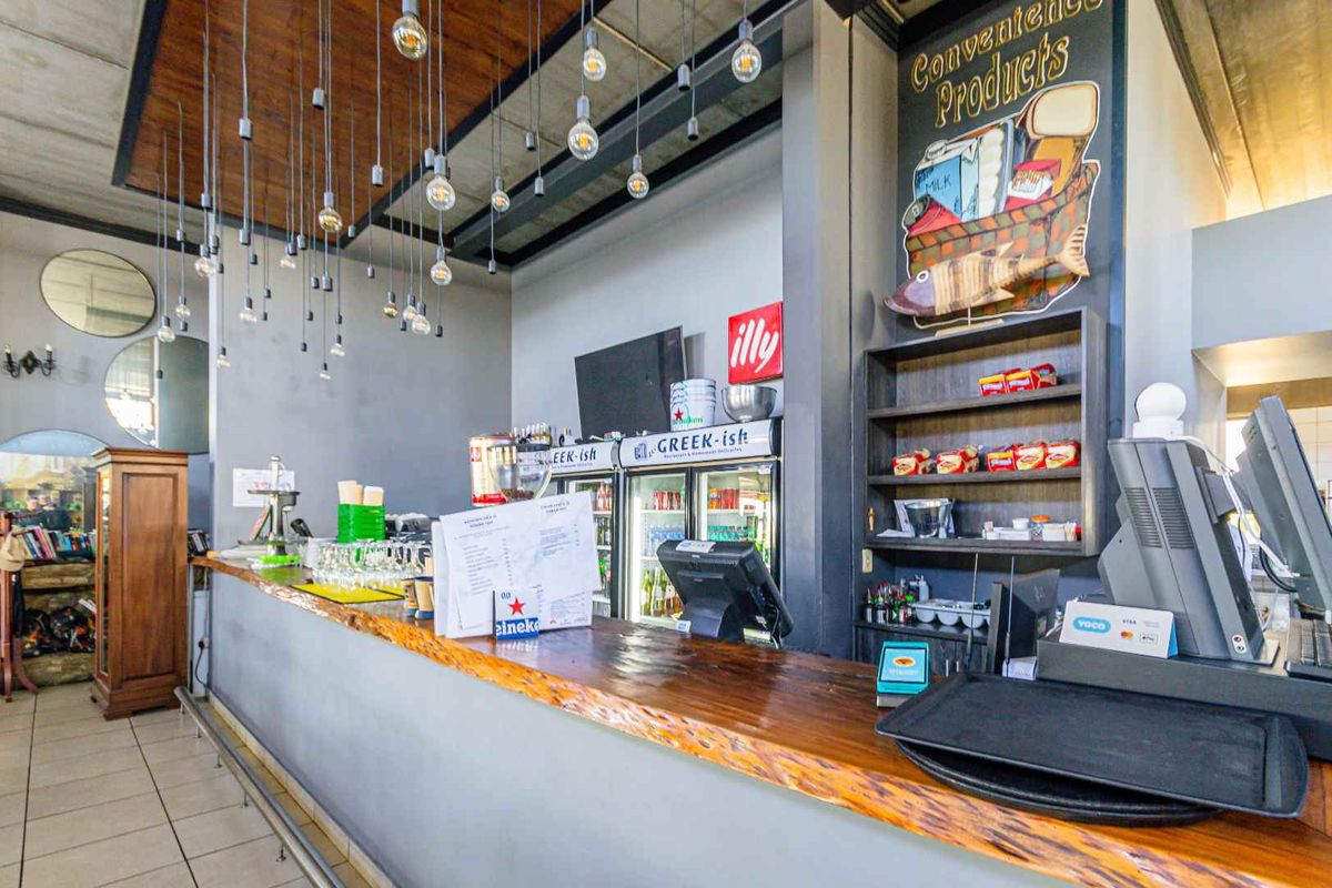A commercial bar area featuring a timber-topped counter, built-in shelving, and modern pendant lighting, suitable for hospitality or entertainment use.
