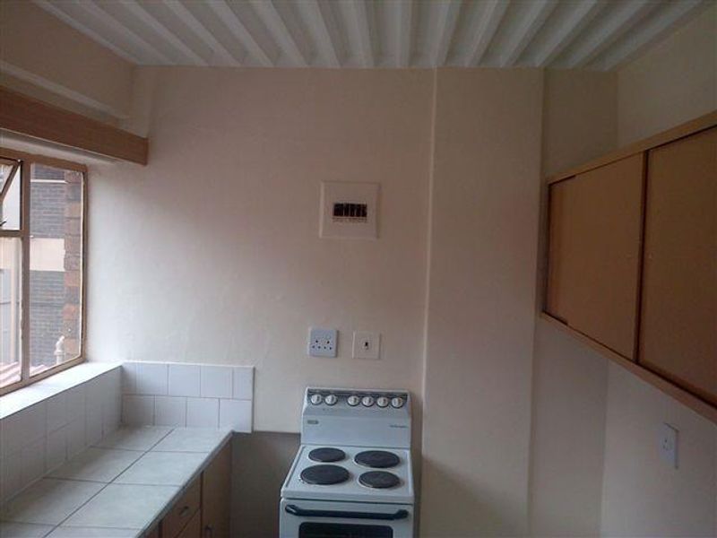 A functional kitchen area featuring a built-in electric stove, tiled countertops, wall-mounted cabinetry, and a tiled splashback.