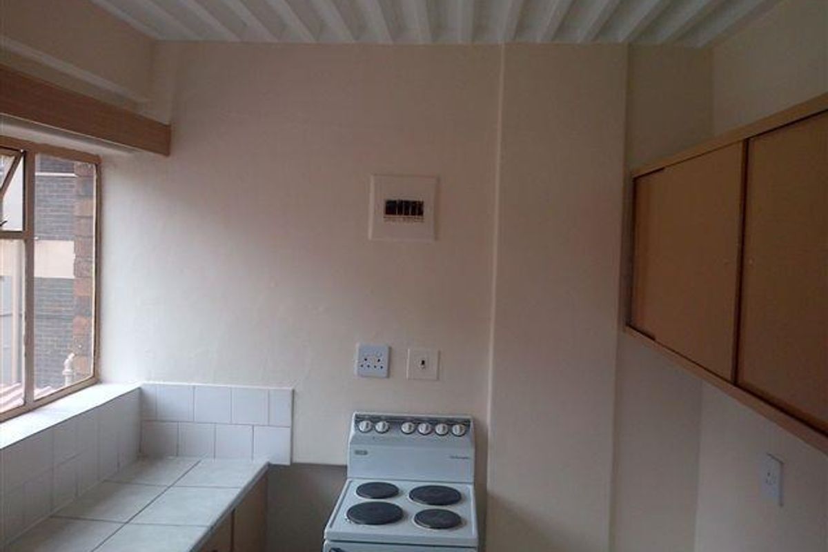 A functional kitchen area featuring a built-in electric stove, tiled countertops, wall-mounted cabinetry, and a tiled splashback.