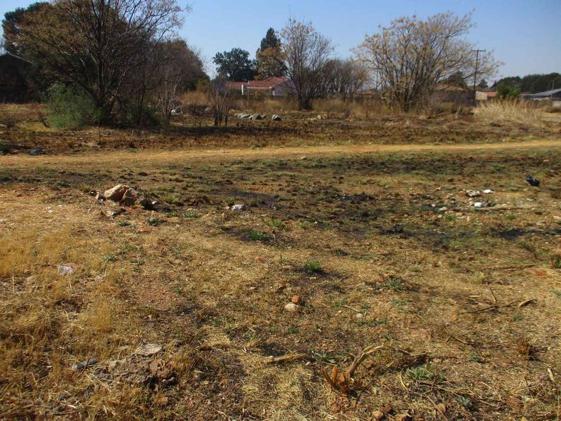 A view of an undeveloped residential vacant land plot featuring dry grass and natural terrain.