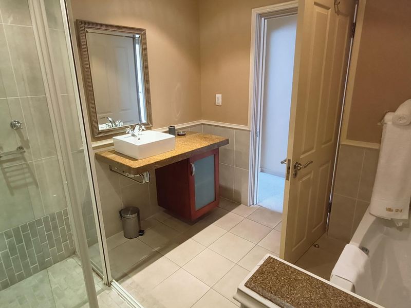A functional bathroom featuring a separate shower enclosure, a bathtub, and a modern vessel sink set on a vanity cabinet.
