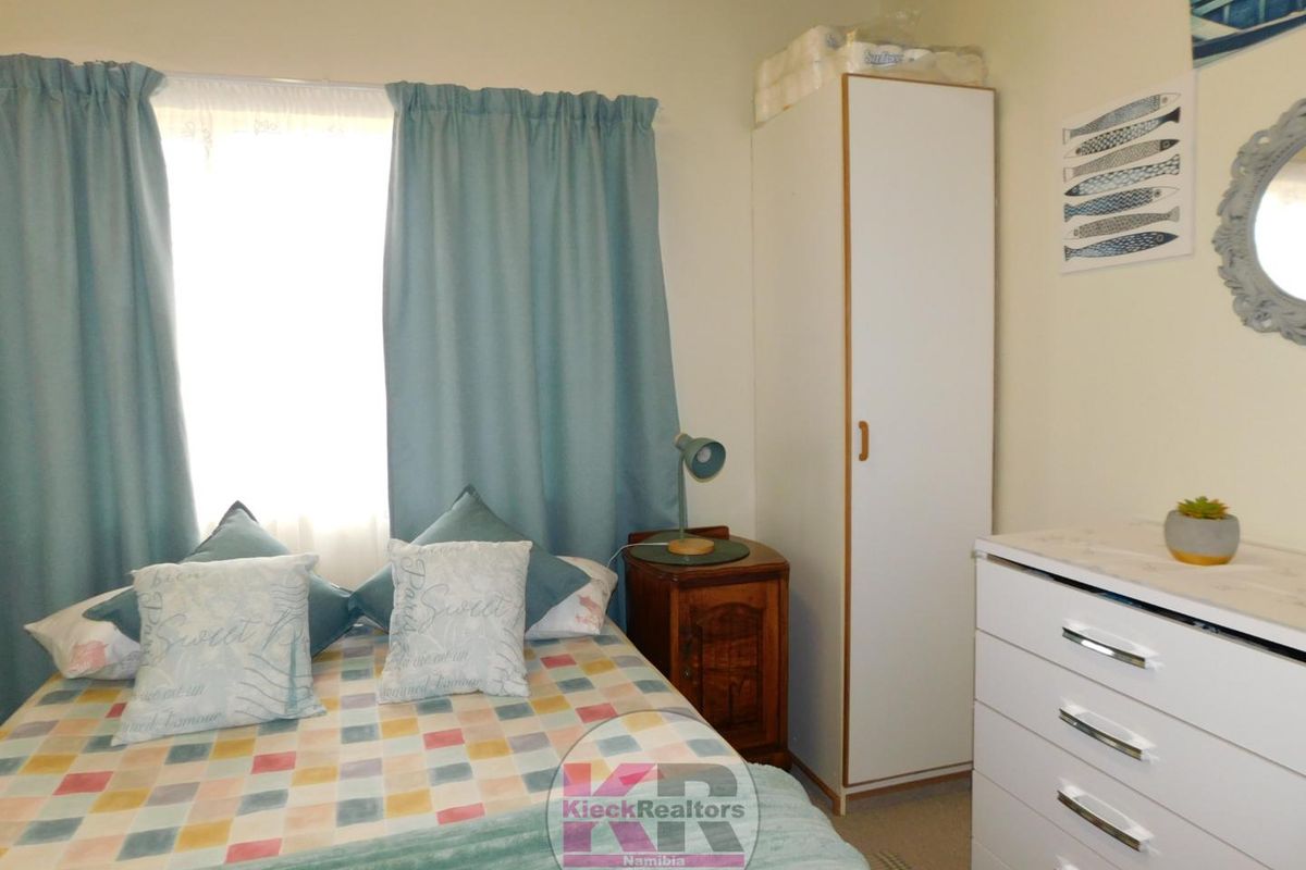 A functional bedroom featuring a built-in wardrobe and natural light from the window.