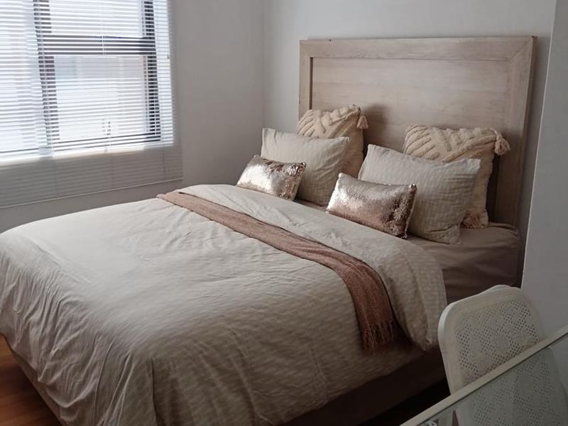 A well-lit bedroom featuring laminate flooring and fitted venetian blinds, providing a neutral and comfortable living space.