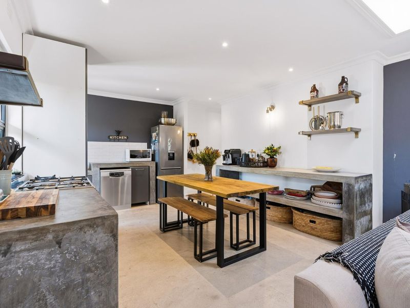 Modern open-plan kitchen and dining area featuring polished concrete surfaces, built-in cabinetry, and contemporary industrial-style finishes.