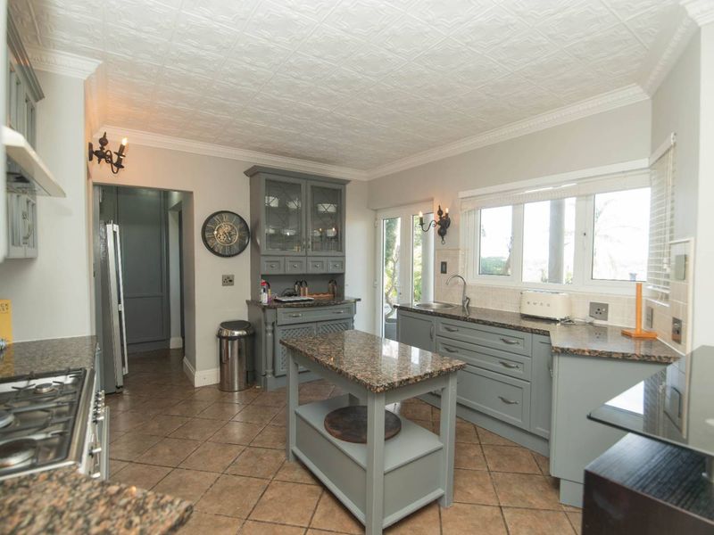 A well-appointed kitchen featuring granite countertops, custom cabinetry, a central island, and a gas hob, with direct access to the outdoor area.
