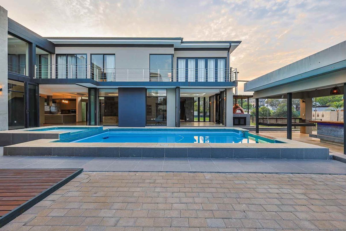 Modern double-story residence featuring a swimming pool, paved patio area, and a covered outdoor entertainment space with a built-in pizza oven.