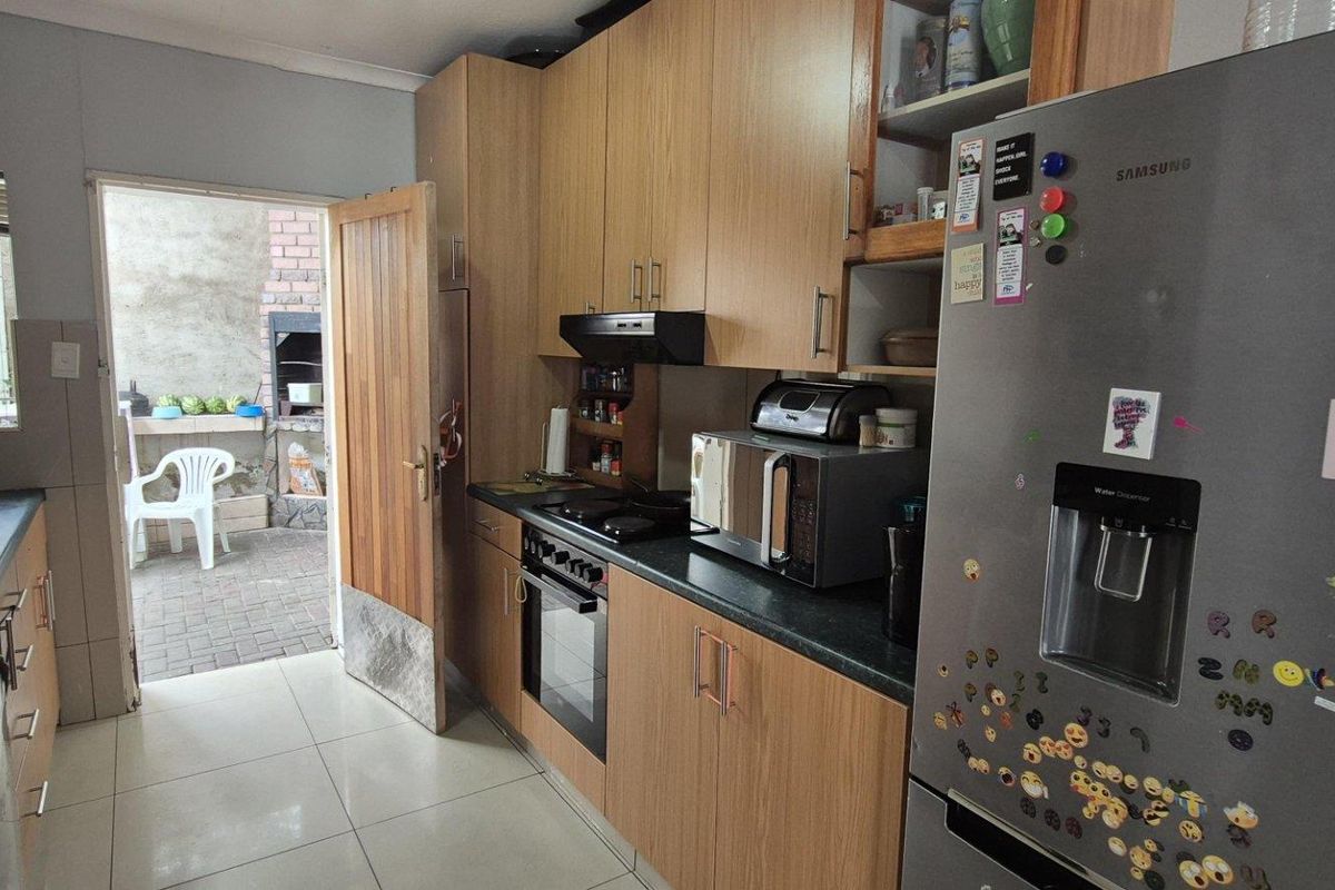 Functional kitchen featuring wood-look cabinetry, dark countertops, built-in oven, and extractor fan, with direct access to an outdoor patio area.