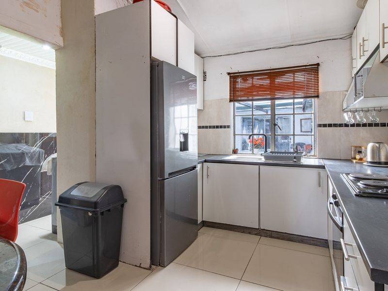 A compact kitchen featuring built-in cabinetry, laminate countertops, and an electric hob, requiring some cosmetic updates to improve its overall condition.