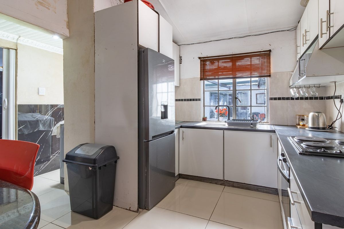 A compact kitchen featuring built-in cabinetry, laminate countertops, and an electric hob, requiring some cosmetic updates to improve its overall condition.