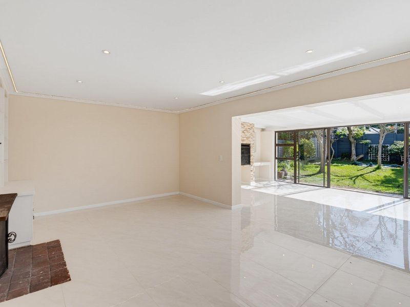 Spacious open-plan living area featuring polished tile floors, recessed lighting, a built-in fireplace, and large sliding doors opening to the garden.