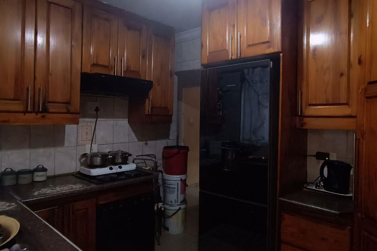 A dated kitchen featuring traditional wooden cabinetry, a tiled backsplash, and built-in cooking appliances, offering potential for a modern renovation.