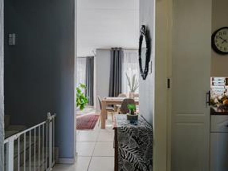 A view from the hallway looking through to the open plan dining and living area, featuring tiled flooring and a staircase access point.