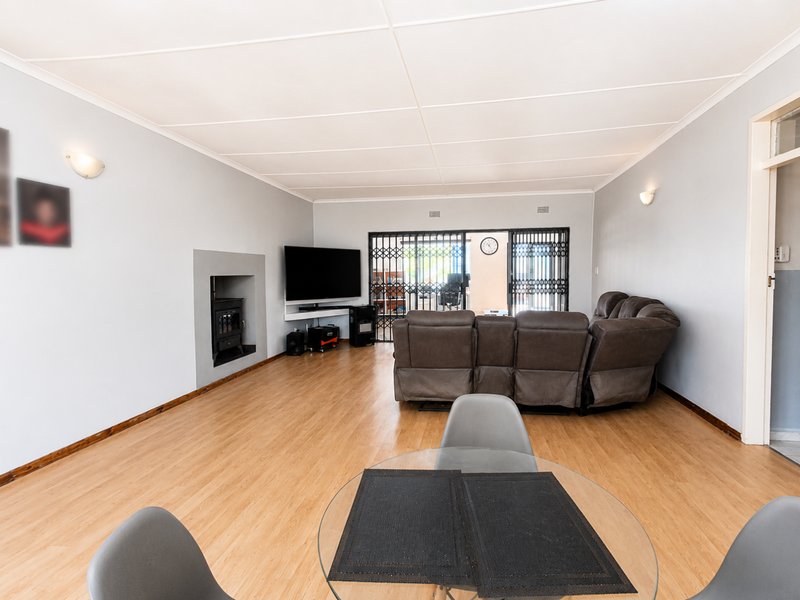 Spacious living room featuring laminate flooring, a built-in fireplace, and sliding doors leading to an outdoor area with security gates.