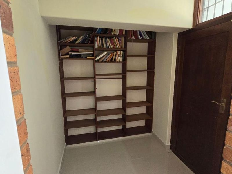 A functional hallway area featuring built-in timber shelving and tiled flooring, providing useful storage space within the home.