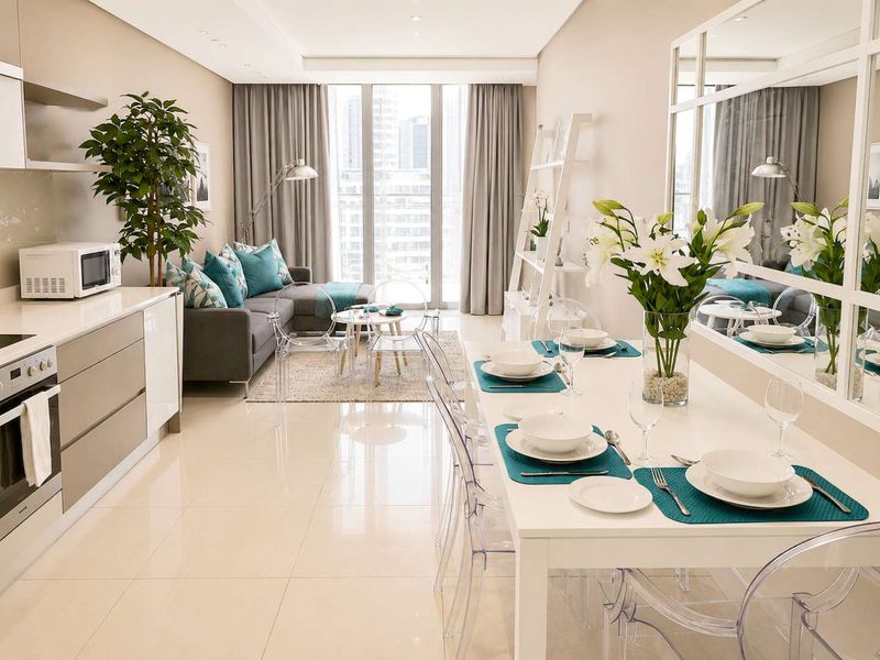Modern open-plan apartment featuring a sleek kitchen, dining area, and living space with large windows and high-quality finishes.