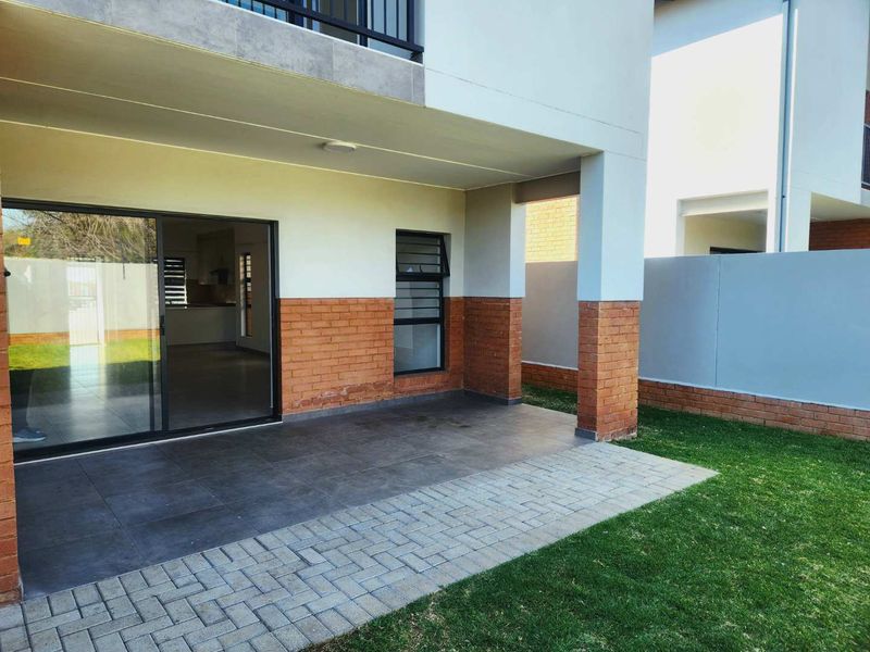 A covered patio area featuring tiled flooring, brick accents, and a sliding glass door providing access to the interior living space.