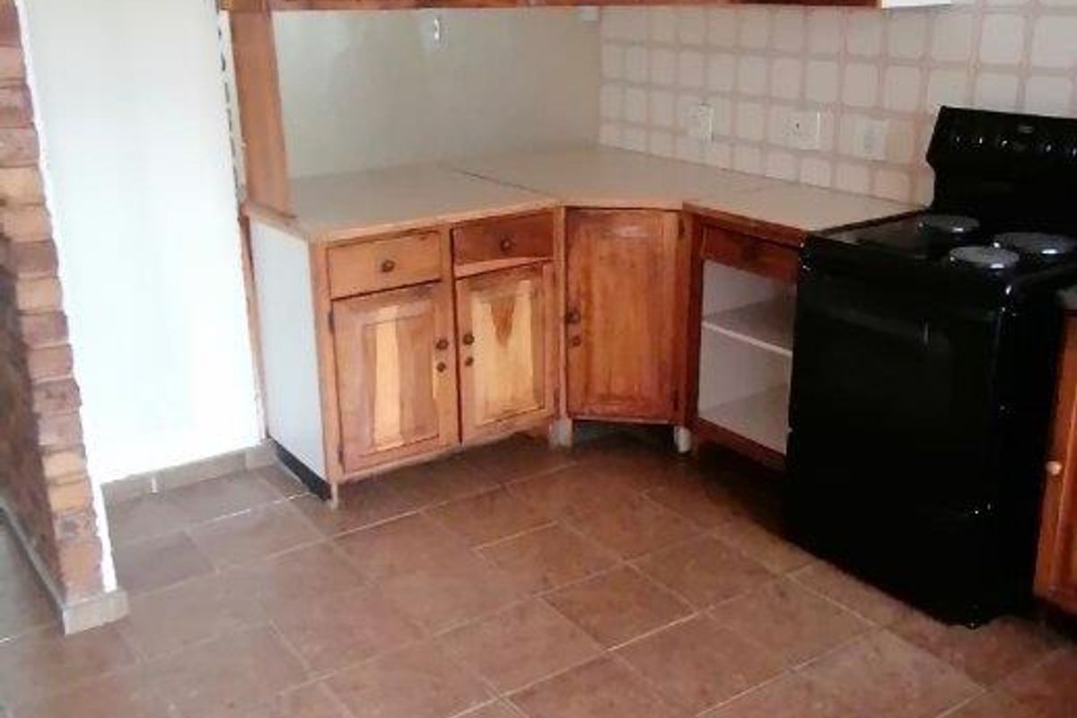A functional kitchen featuring wooden cabinetry, tiled backsplash, and tiled flooring, currently awaiting updates to modernize the space.
