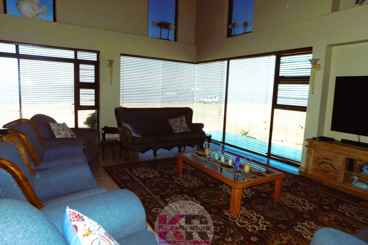 Spacious living room featuring high ceilings, large windows with fitted blinds, and ample natural light.