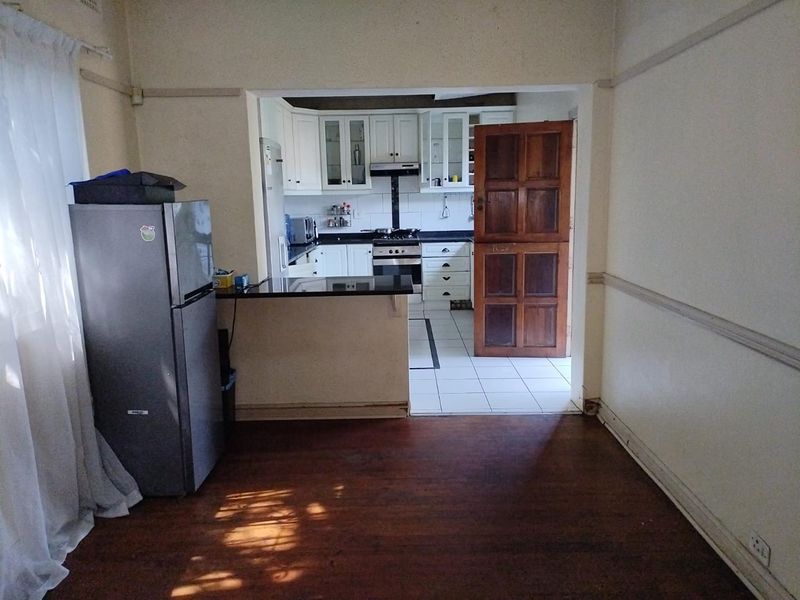 Open plan living area flowing into a functional kitchen featuring granite countertops, gas stove, and tiled flooring.