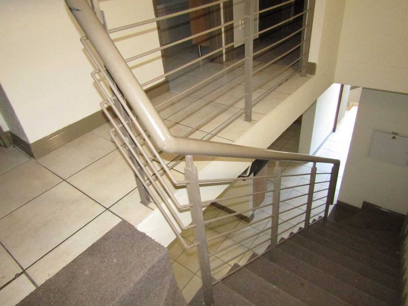 A functional staircase area featuring metal balustrades and tiled landing, connecting different levels of the townhouse.