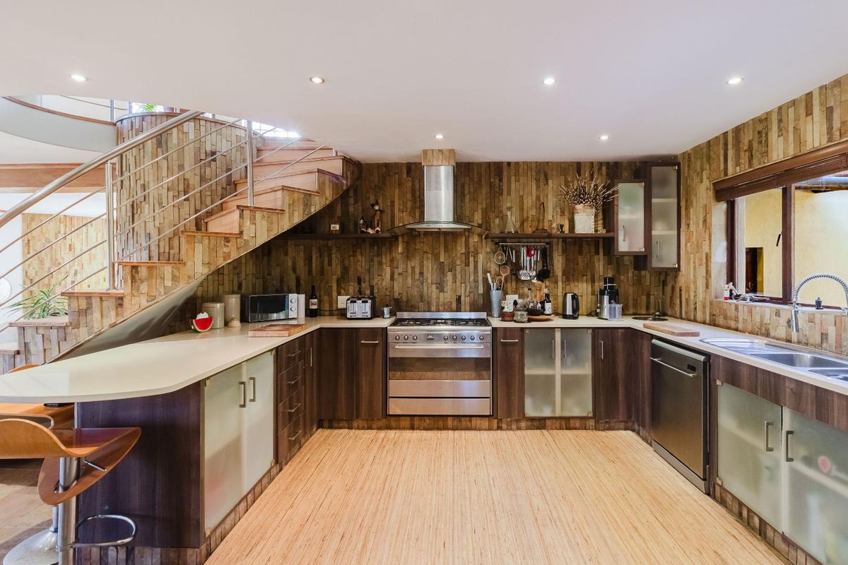 Modern kitchen featuring dark wood cabinetry, stainless steel appliances, stone cladding accents, and an integrated staircase, creating a unique and functional culinary space.