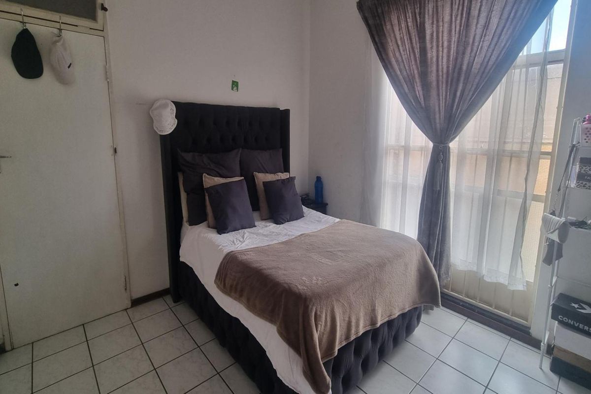 A bedroom featuring tiled flooring and a sliding glass door providing natural light.