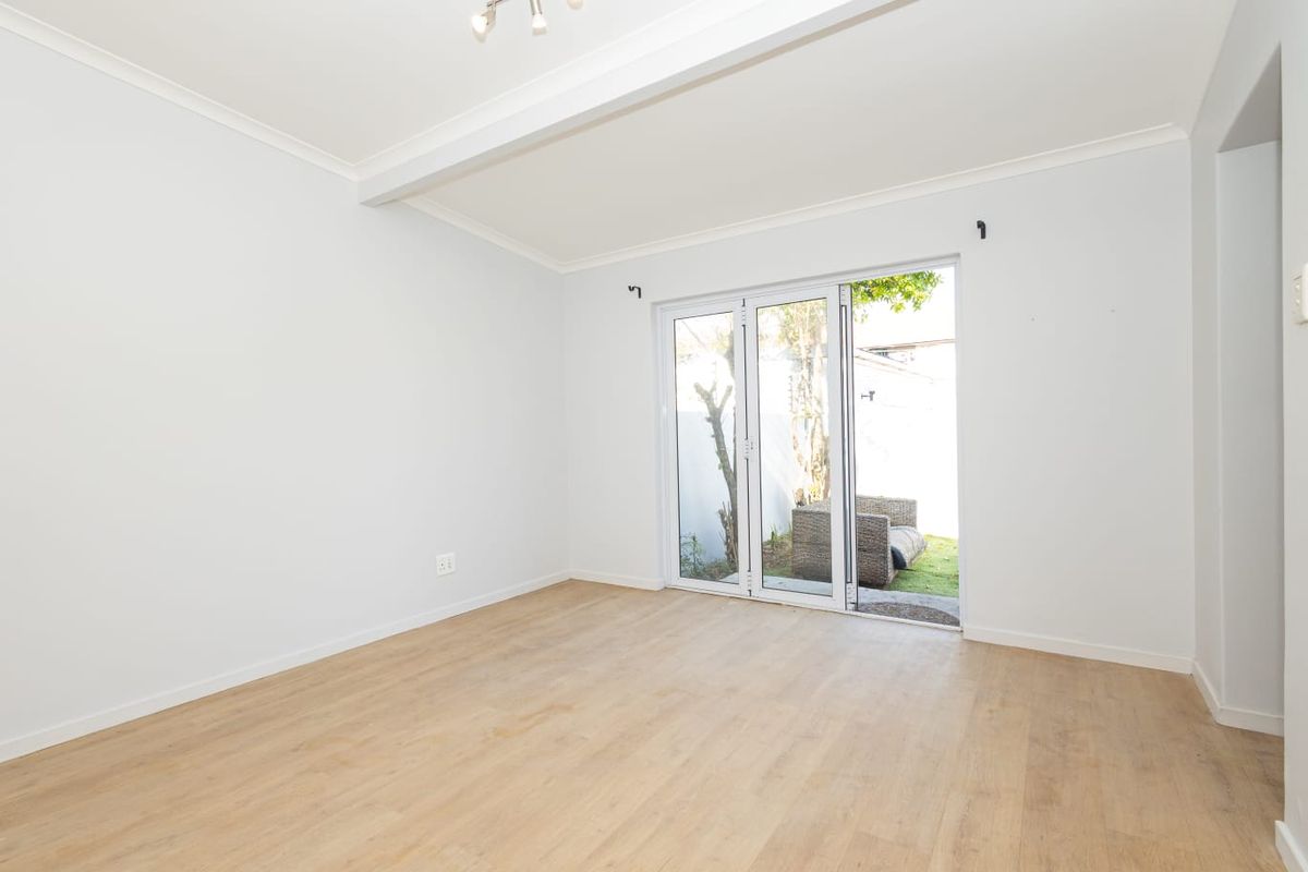 Bright and spacious living area featuring light-toned laminate flooring and bi-fold glass doors providing direct access to the rear garden.