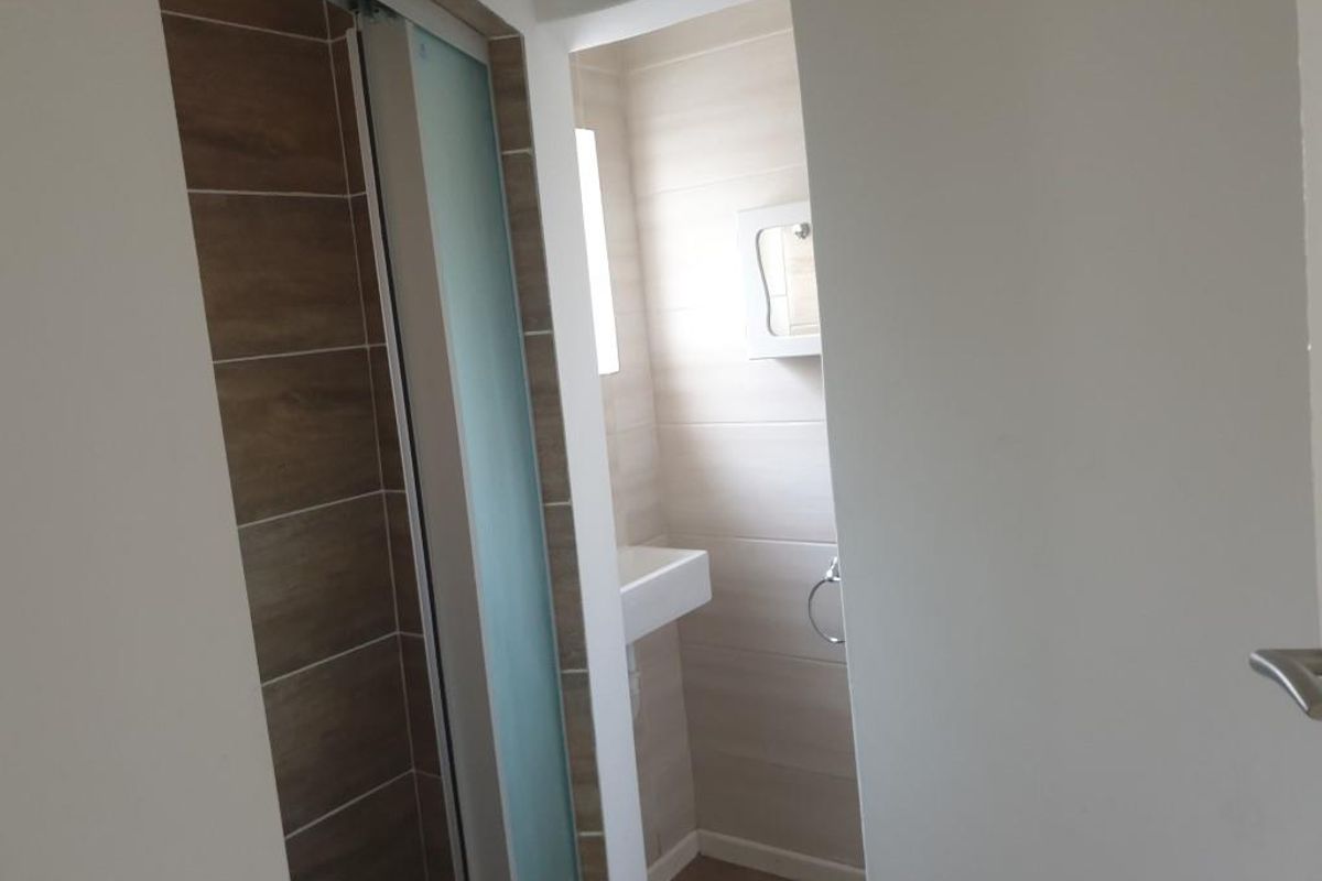 A clean, modern bathroom featuring a shower enclosure with wood-look tiling and a wall-mounted basin.