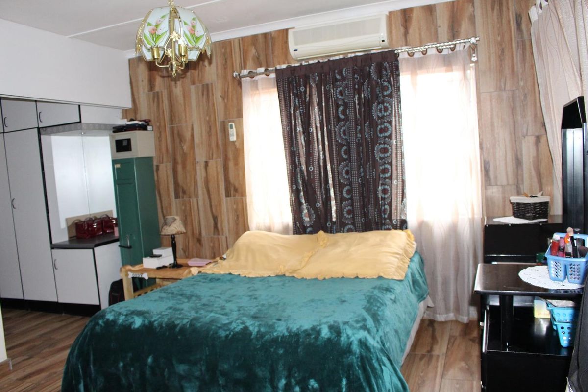 A bedroom featuring wood-look wall paneling, built-in cabinetry, and a wall-mounted air conditioning unit.
