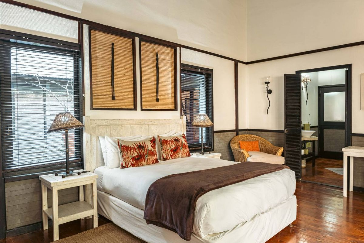 A well-maintained bedroom featuring high ceilings, dark wood flooring, and an en-suite bathroom with a vanity.