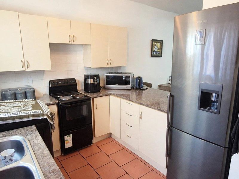 Functional kitchen featuring laminate cabinetry, granite-look countertops, a double bowl stainless steel sink, and durable ceramic floor tiles.