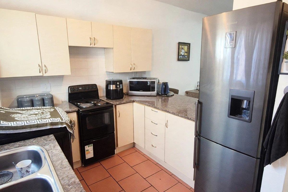 Functional kitchen featuring laminate cabinetry, granite-look countertops, a double bowl stainless steel sink, and durable ceramic floor tiles.