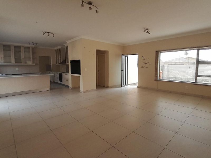 Spacious open-plan living and kitchen area featuring tiled flooring, built-in cabinetry, a kitchen island, and a built-in fireplace, offering a bright and versatile layout.