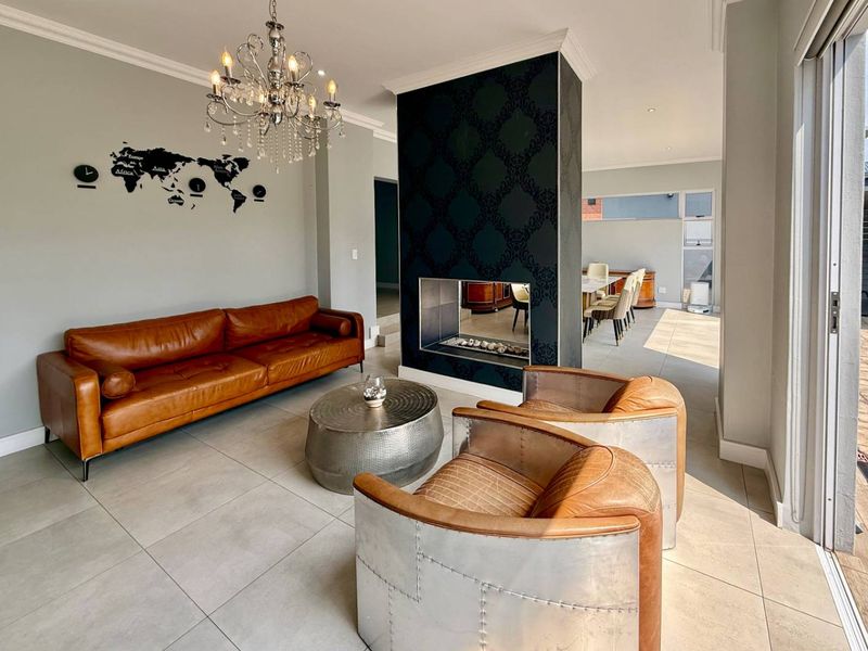 Spacious open-plan living area featuring a modern double-sided fireplace, large format floor tiles, and seamless access to the outdoor patio.