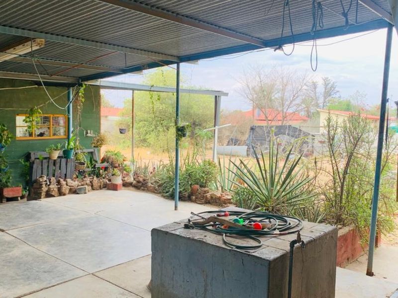 A covered outdoor patio area featuring a corrugated metal roof, concrete flooring, and a built-in concrete plinth with an outdoor water tap.
