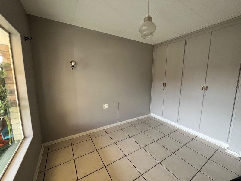 An empty bedroom featuring tiled flooring, built-in cupboards, and neutral wall finishes, offering a blank canvas for personalization.