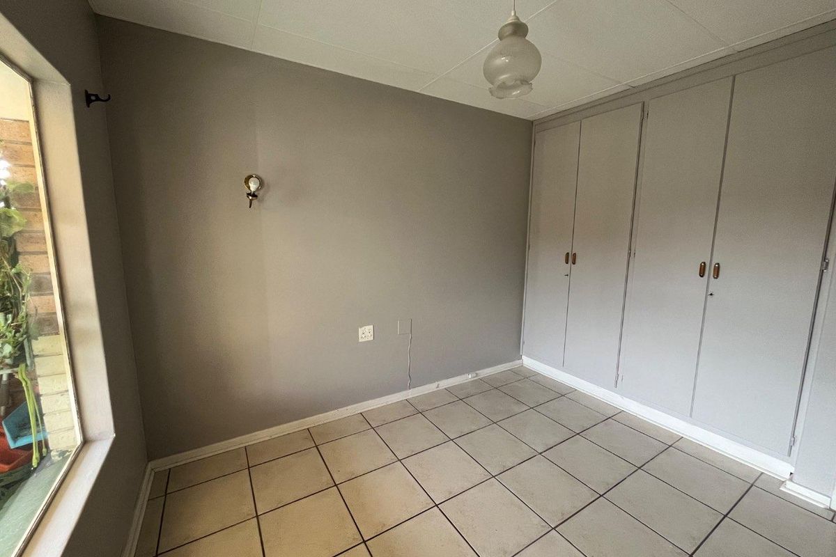 An empty bedroom featuring tiled flooring, built-in cupboards, and neutral wall finishes, offering a blank canvas for personalization.
