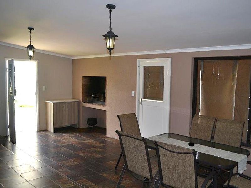 Covered patio area featuring tiled flooring, built-in braai, and direct access to the exterior, suitable for outdoor dining and entertainment.