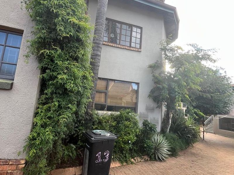 Front elevation of a two-story house featuring a paved driveway, stucco exterior, and established garden landscaping.
