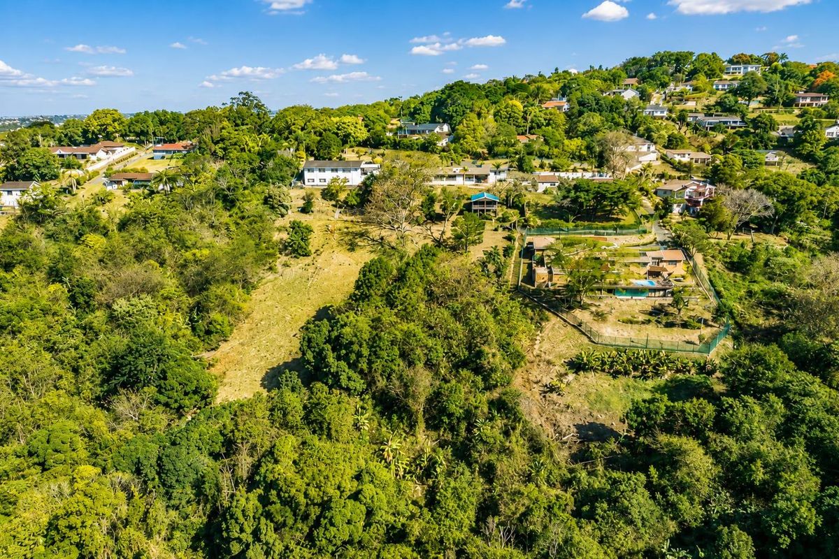 An aerial view of the property showing the surrounding landscape, residential neighborhood, and the home's outdoor pool area.