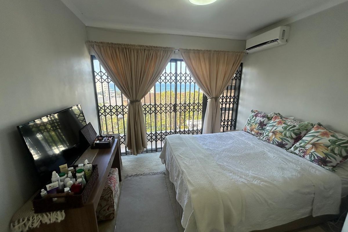 A bedroom featuring an air conditioning unit and a sliding door with a security gate, providing access to an outdoor area with a view.