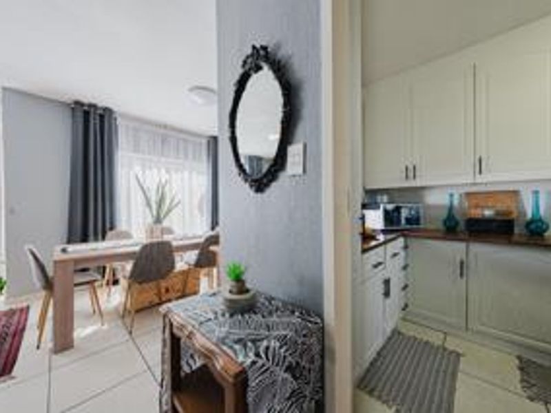 An open-plan living and dining area adjacent to a compact kitchen featuring white cabinetry and tiled flooring.