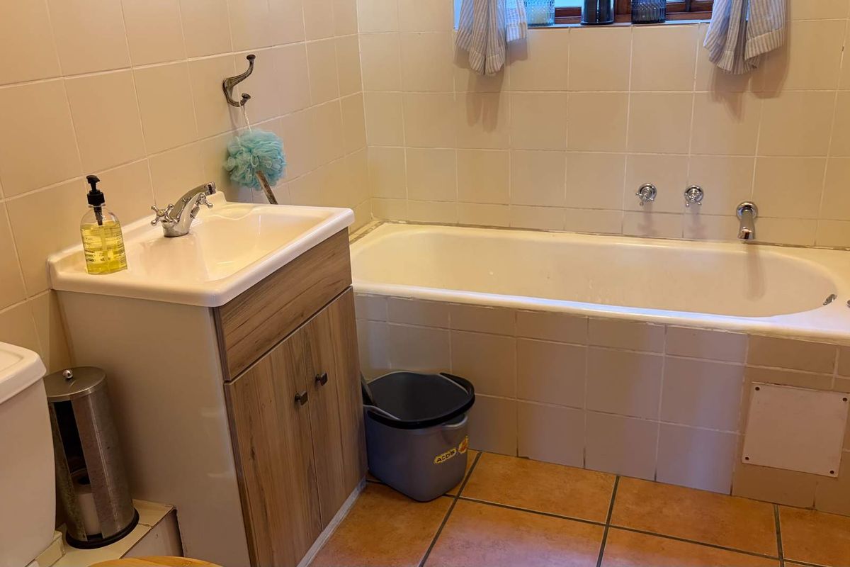 A functional bathroom featuring a built-in bathtub, vanity basin, and tiled walls and flooring.