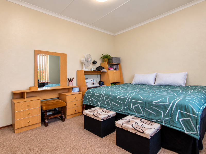 A functional bedroom featuring neutral wall finishes, carpeted flooring, and coved ceiling detailing.