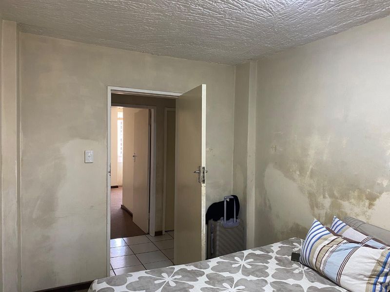 A bedroom interior showing significant wall staining and surface deterioration, requiring maintenance and cosmetic updates to improve the living space.