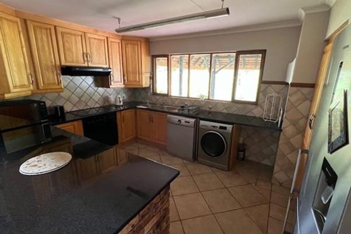 A functional kitchen featuring wooden cabinetry, dark granite countertops, tiled backsplash, and integrated appliance spaces with a breakfast bar area.