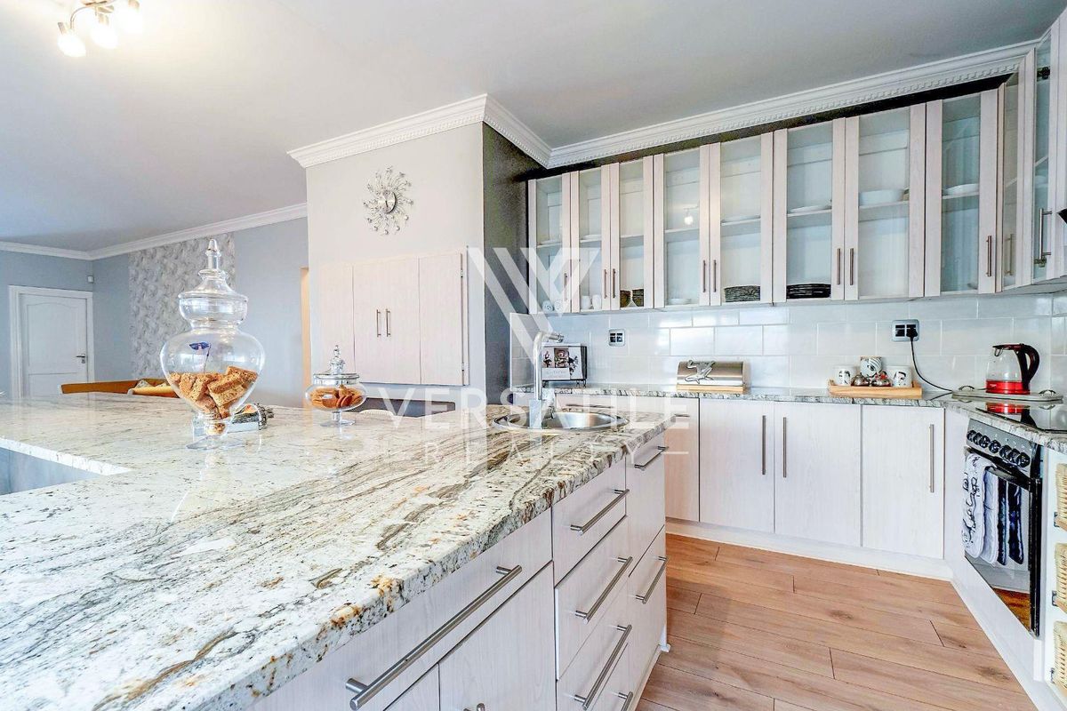 Modern kitchen featuring granite countertops, glass-fronted cabinetry, subway tile backsplash, and high-quality built-in appliances with elegant crown molding details.