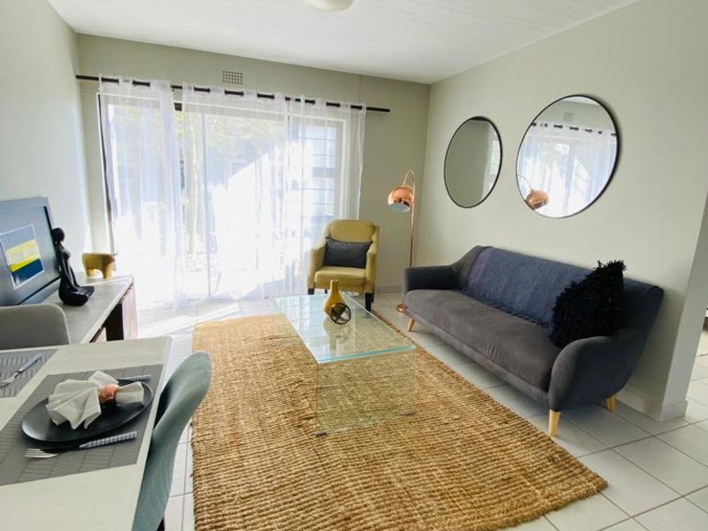 Bright open-plan living and dining area featuring neutral tiled flooring and a large sliding glass door providing access to the exterior.